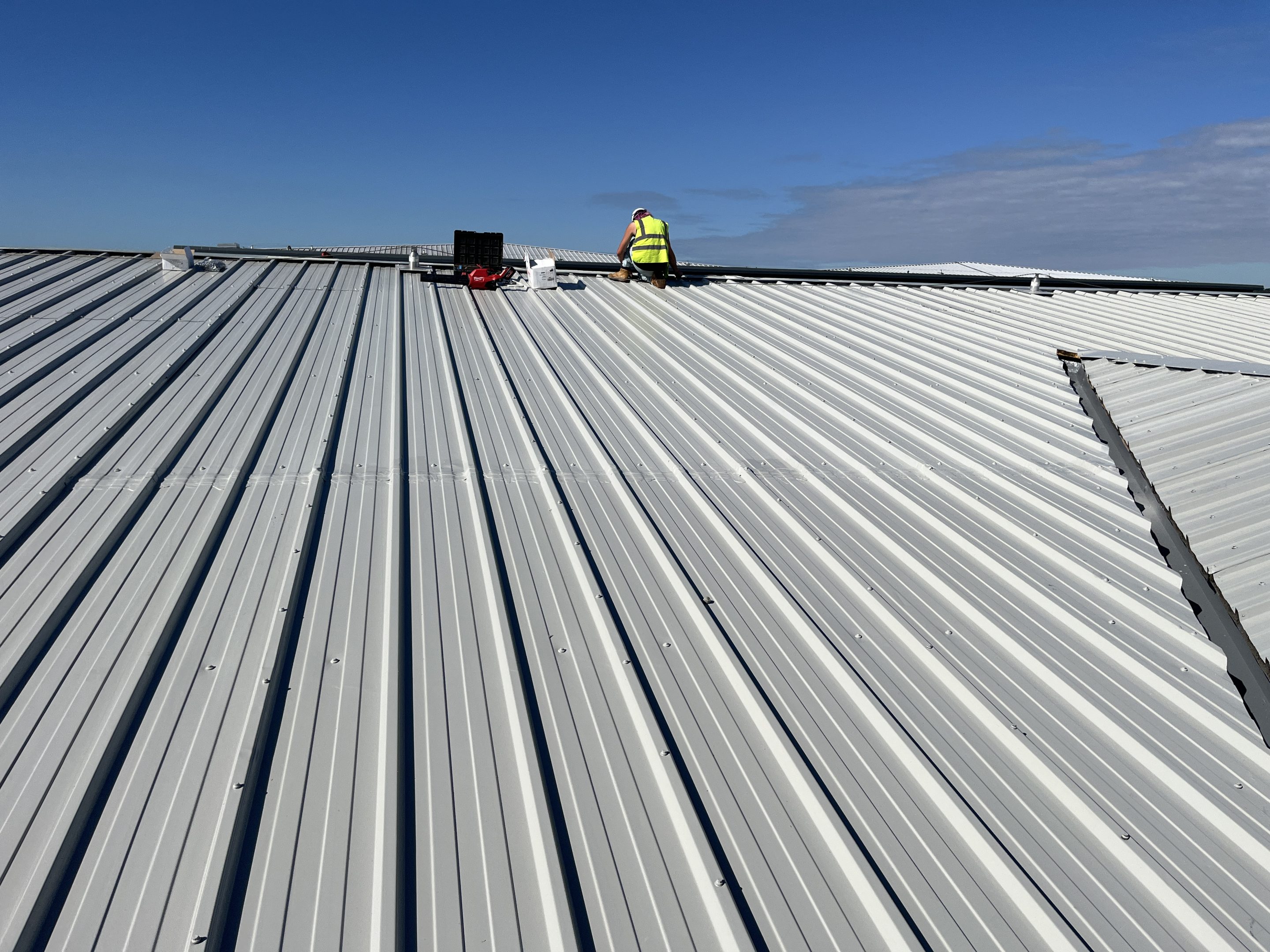 Image showing a metal roof coating project completed using Liquasil's Metalseal 20 system, with sealed mid-lap joints using Liquasil HP Butyl Tape