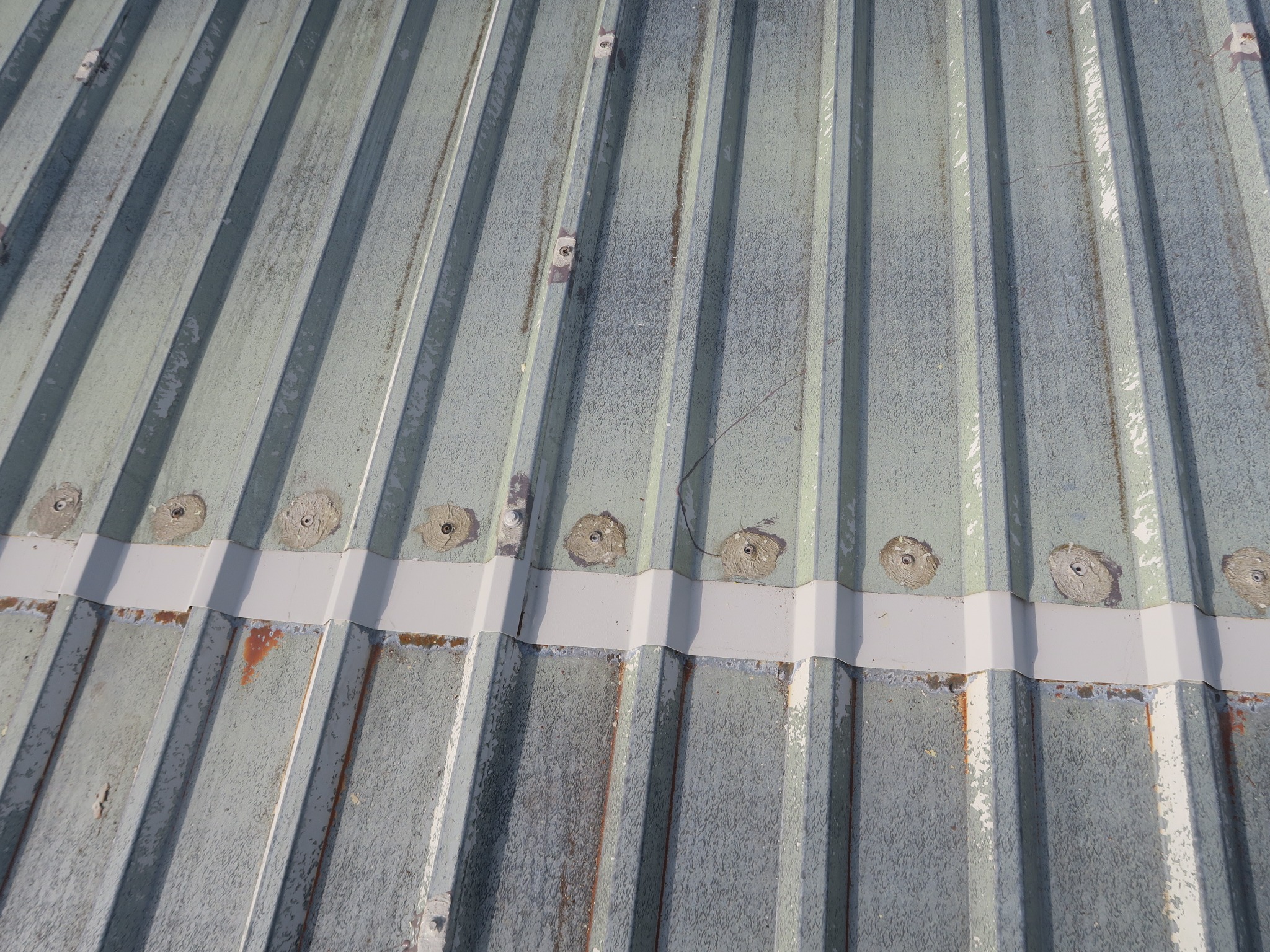 Image showing new profiled repair sections installed over the remaining upper sheets and fixed through butyl tape beneath.