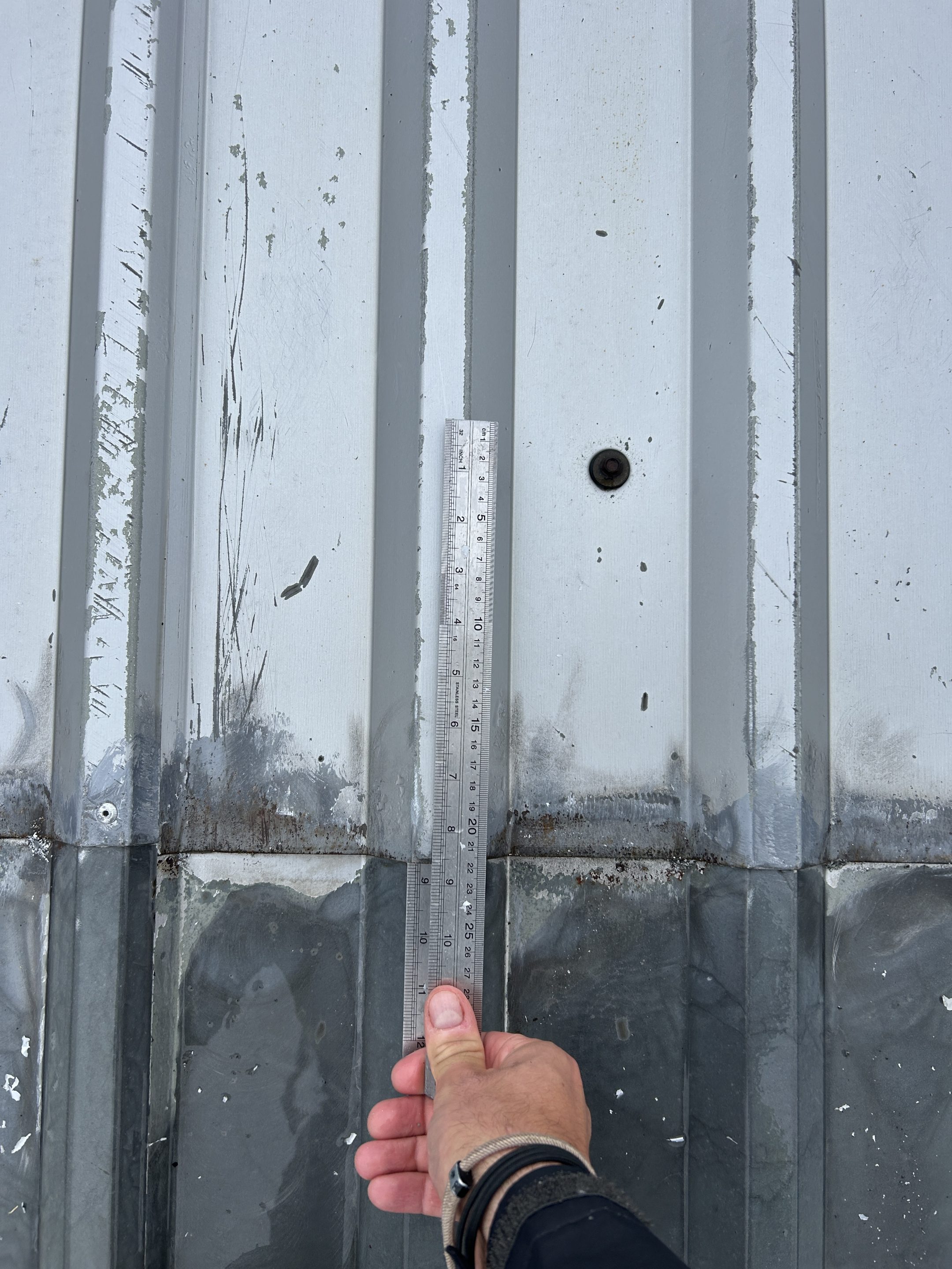 image showing an inspection to determine whether a butyl strip ise present at a mid-lap joint on a steel profiled roof.