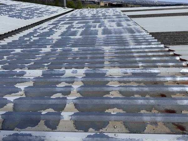 Image showing the loss of plastisol finish to large areas of a steel roof with resultant spot-corrosion evident