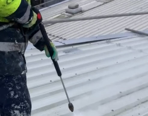 Jet washing a metal roof before coating with Liquasil's Metalseal 20.