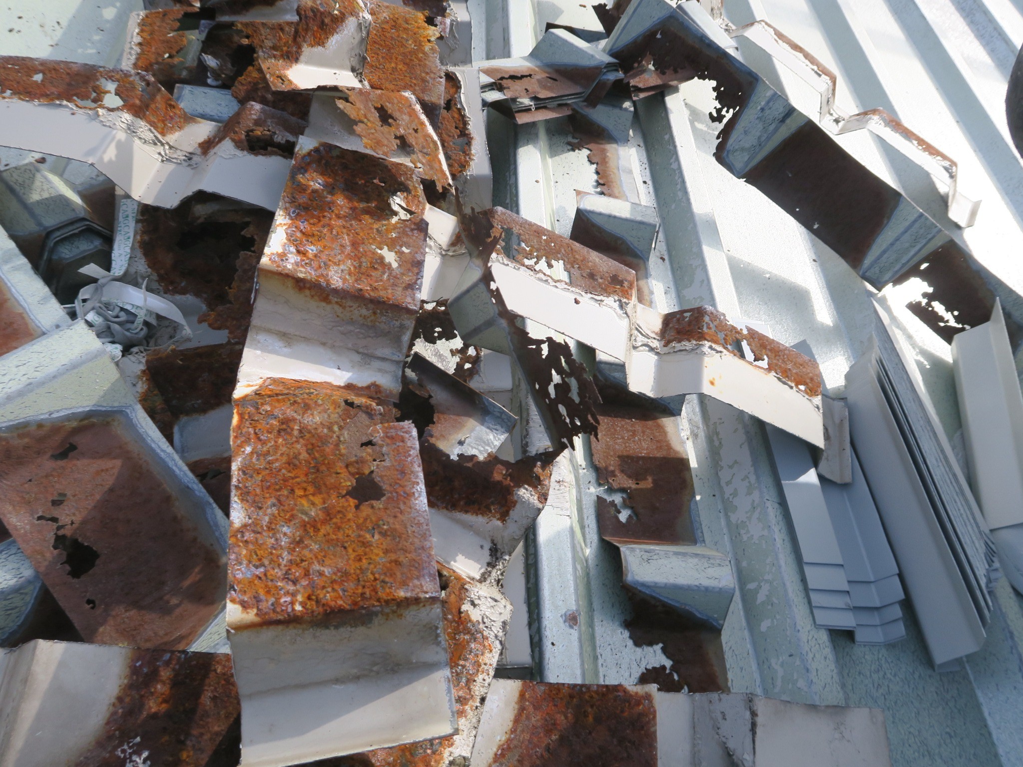 image showing removed sections from corroded roof sheet ends, with extensive corrosion, perforations and loss of steel
